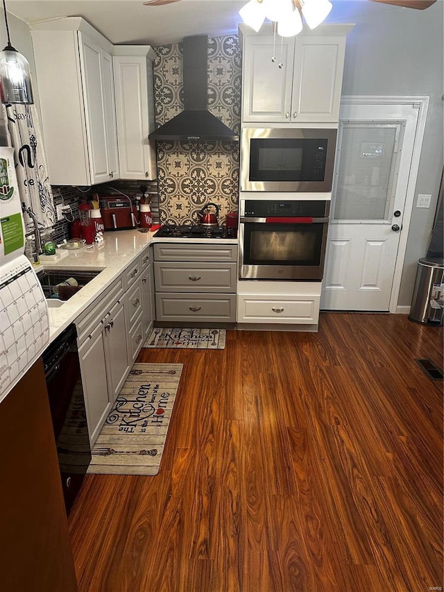 kitchen featuring oven, built in microwave, gray cabinets, gas stovetop, and wall chimney exhaust hood