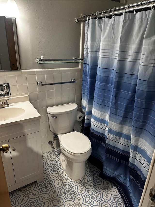 full bathroom featuring tile patterned floors, toilet, curtained shower, tile walls, and vanity