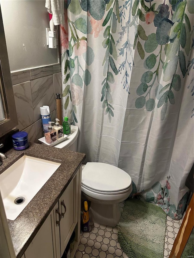 full bath with curtained shower, toilet, vanity, tile patterned floors, and tile walls