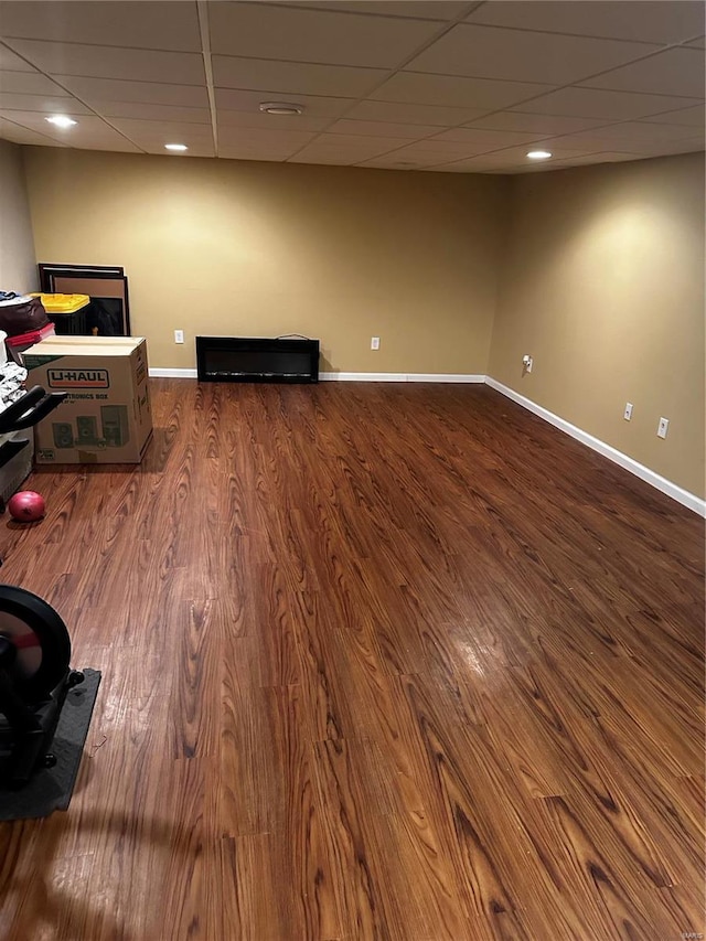 interior space with a paneled ceiling, baseboards, and dark wood-style flooring