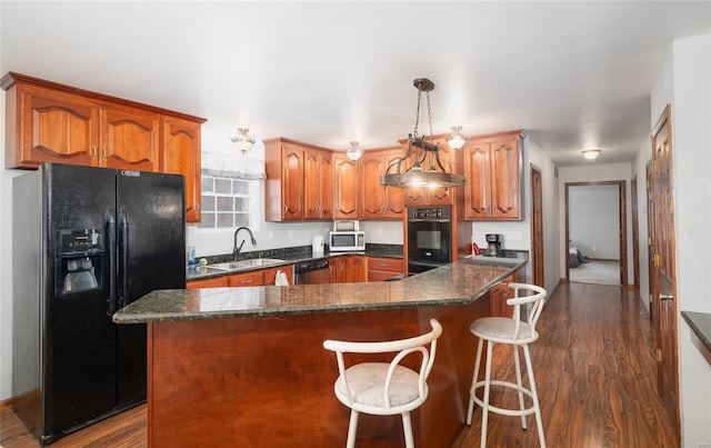 kitchen with dark wood-style floors, brown cabinets, a sink, and black appliances