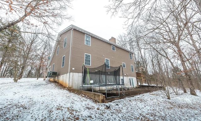 snow covered property featuring a trampoline and a chimney