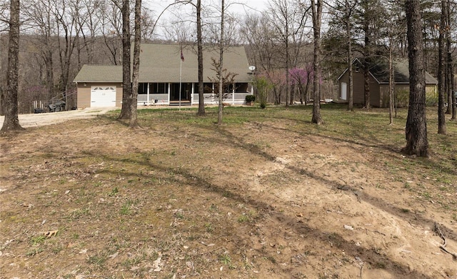 view of front of property with dirt driveway and a garage