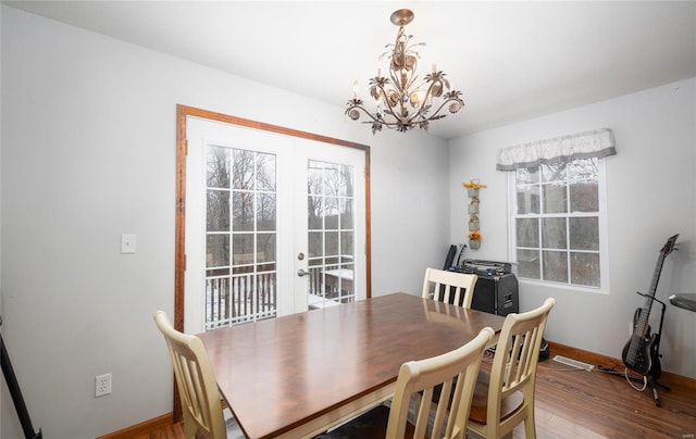 dining space featuring wood finished floors, baseboards, french doors, and an inviting chandelier