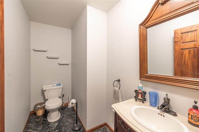 bathroom featuring toilet, marble finish floor, vanity, and baseboards