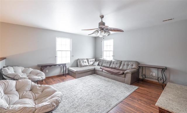 living room featuring visible vents, a ceiling fan, and dark wood-style floors