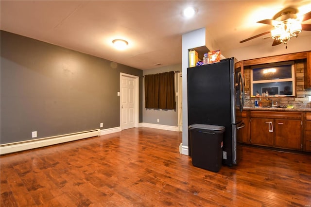 kitchen featuring dark wood-style floors, baseboard heating, ceiling fan, and freestanding refrigerator