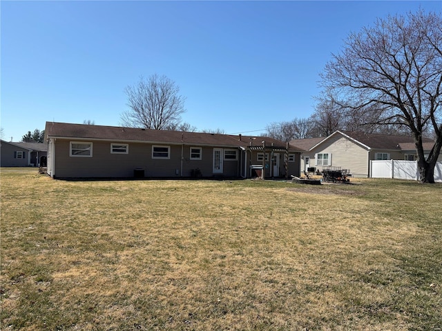 back of property with a lawn and fence