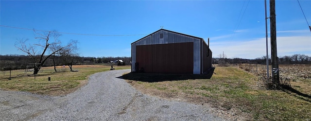 view of outbuilding featuring an outbuilding, gravel driveway, and a rural view