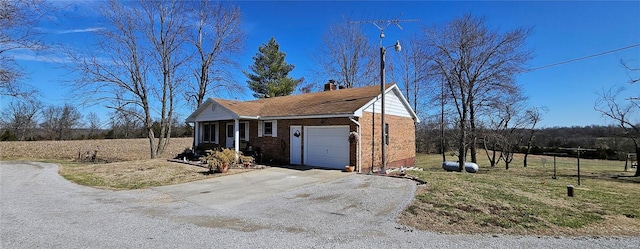 view of front of home featuring a front yard, driveway, an attached garage, a chimney, and brick siding