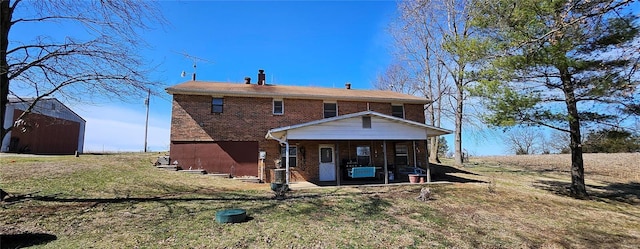 back of property featuring brick siding and a lawn