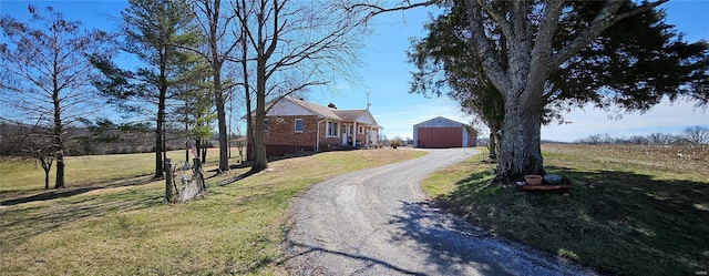 view of front of house featuring a pole building, driveway, an outdoor structure, a front lawn, and brick siding