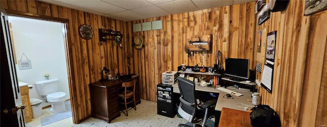 home office featuring wooden walls and a drop ceiling