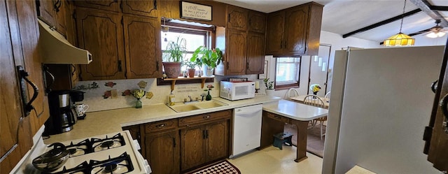 kitchen with decorative backsplash, white appliances, light countertops, and a sink