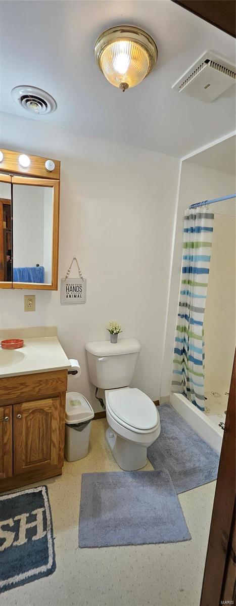 full bathroom with vanity, toilet, visible vents, and a stall shower