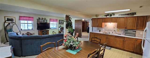 kitchen with brown cabinets, a sink, freestanding refrigerator, light countertops, and light floors