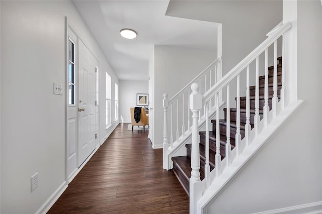 entryway with dark wood-type flooring, stairway, and baseboards