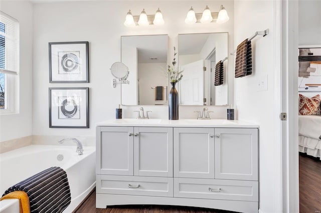 ensuite bathroom with double vanity, a sink, a bath, and ensuite bathroom