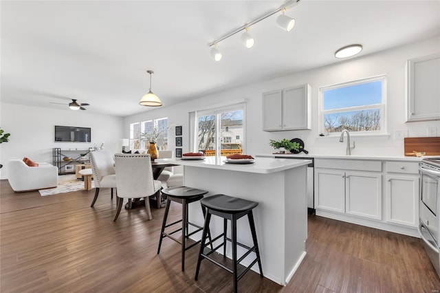 kitchen featuring a center island, a breakfast bar, dark wood-style flooring, decorative light fixtures, and light countertops