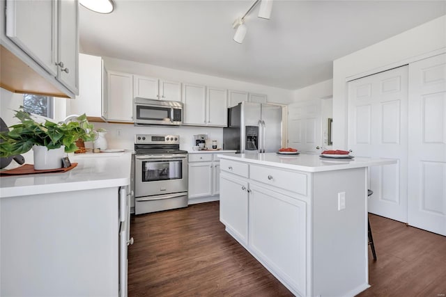 kitchen with light countertops, appliances with stainless steel finishes, dark wood-type flooring, and a kitchen island