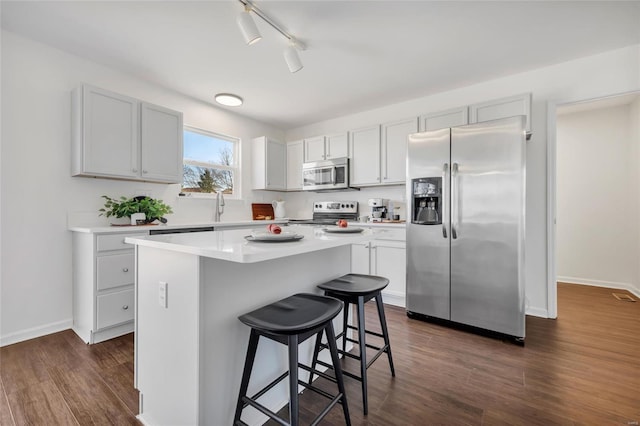 kitchen featuring dark wood-style floors, a center island, stainless steel appliances, and a kitchen breakfast bar