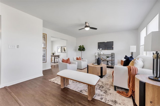 living room with a ceiling fan, baseboards, and wood finished floors