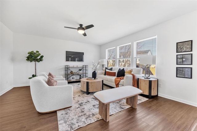 living area featuring ceiling fan, baseboards, and wood finished floors