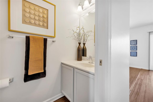 bathroom with baseboards, wood finished floors, and vanity