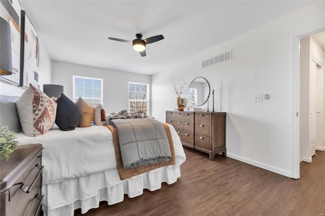 bedroom with a ceiling fan, visible vents, baseboards, and wood finished floors