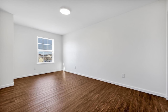 spare room featuring dark wood-type flooring and baseboards