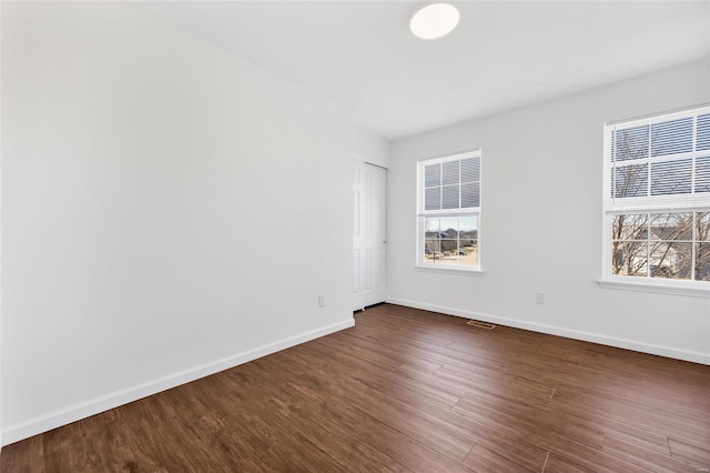 empty room featuring baseboards and dark wood-style flooring