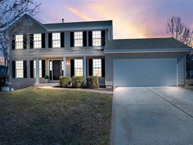 colonial home featuring a garage, a front yard, driveway, and a shingled roof