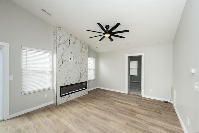 unfurnished living room featuring vaulted ceiling, visible vents, light wood-style floors, and a premium fireplace