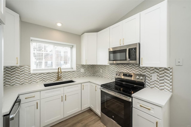 kitchen with a sink, light countertops, white cabinets, appliances with stainless steel finishes, and backsplash