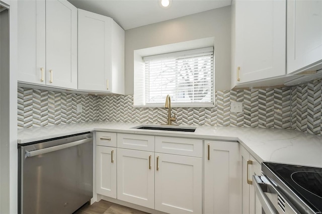 kitchen with light stone countertops, a sink, decorative backsplash, appliances with stainless steel finishes, and white cabinetry