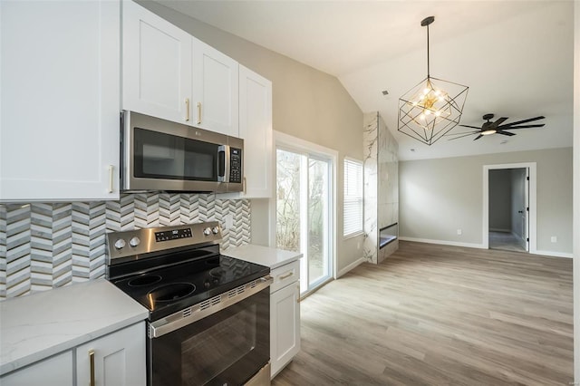 kitchen with tasteful backsplash, light wood-type flooring, lofted ceiling, white cabinets, and stainless steel appliances