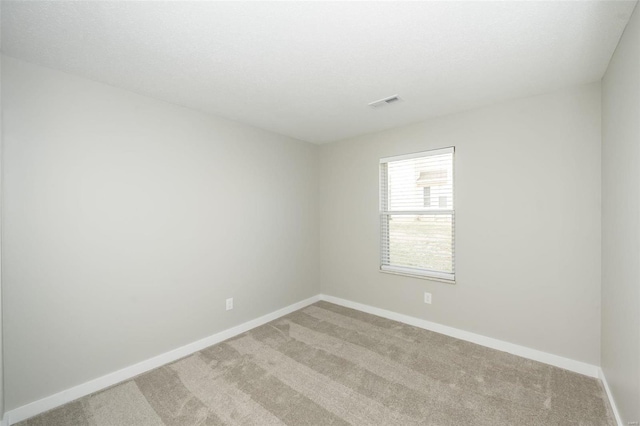 empty room featuring light carpet, visible vents, and baseboards