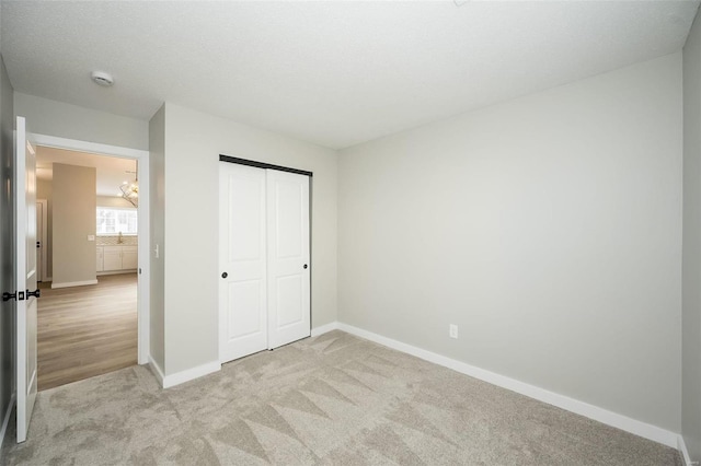 unfurnished bedroom with a sink, a closet, baseboards, and carpet flooring