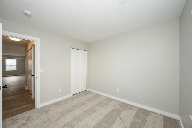 unfurnished bedroom with a closet, baseboards, and carpet flooring