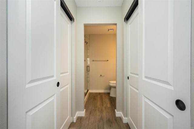 interior space featuring visible vents, baseboards, a barn door, and wood finished floors