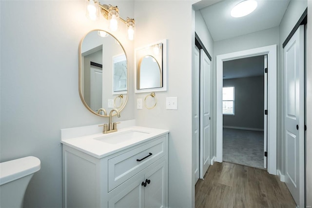 bathroom featuring vanity, toilet, wood finished floors, and baseboards