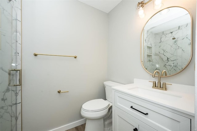 full bath featuring a marble finish shower, baseboards, toilet, wood finished floors, and vanity