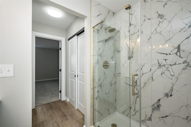 full bathroom featuring a marble finish shower and wood finished floors