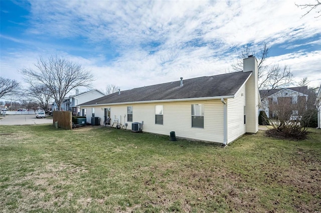 back of property featuring a yard, central AC, and a chimney