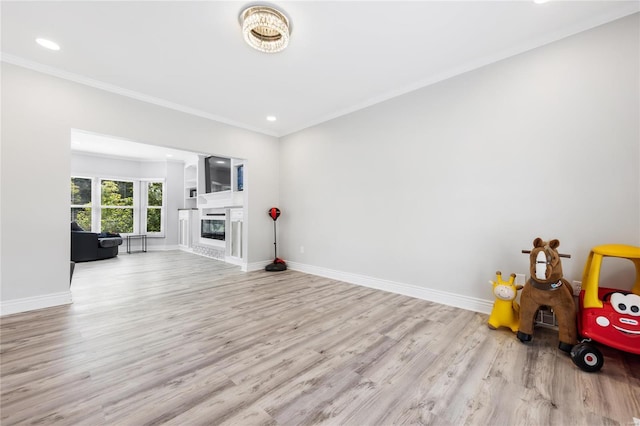 living room featuring ornamental molding, a glass covered fireplace, wood finished floors, and baseboards