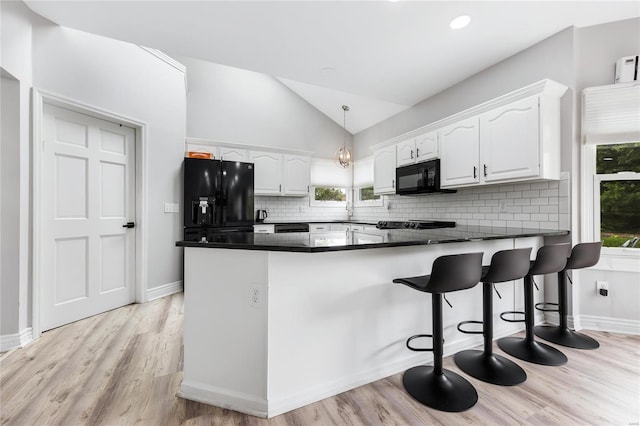 kitchen with a peninsula, white cabinets, backsplash, black appliances, and dark countertops