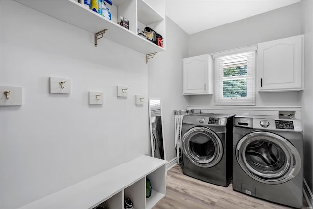 laundry area featuring cabinet space, light wood-style floors, and washing machine and clothes dryer