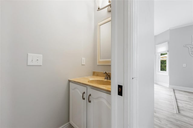 bathroom with wood finished floors, vanity, and baseboards