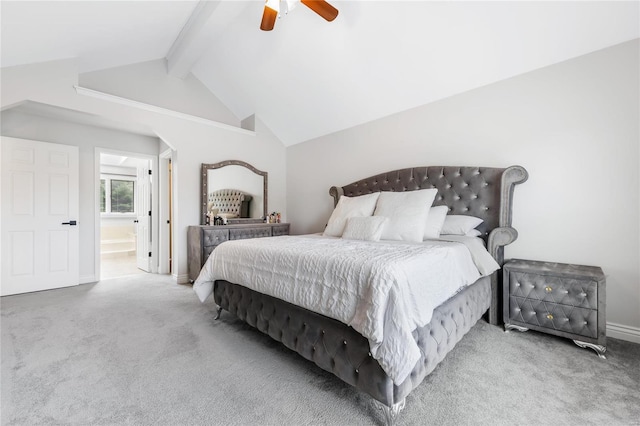 carpeted bedroom with baseboards, arched walkways, a ceiling fan, ensuite bath, and vaulted ceiling with beams