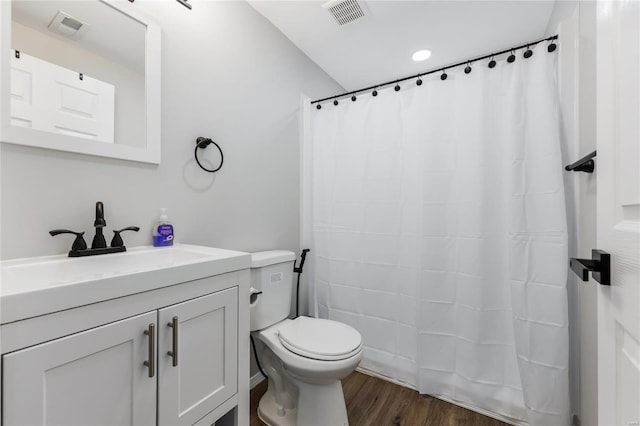 bathroom featuring toilet, visible vents, wood finished floors, and vanity